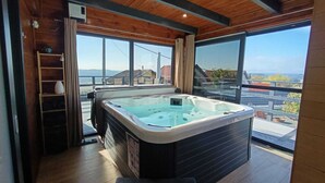 Ein modernes Badezimmer mit einer großen Badewanne, Holzboden und großen Fenstern mit Blick auf die Stadt.