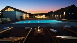 Ein Poolbereich mit Liegestühlen, einem Tisch mit Flasche und Gläsern sowie einem Schwimmbecken.