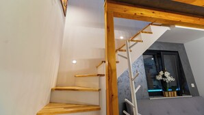 Una escalera de madera con diseño moderno, una ventana con vistas y una planta en el alféizar.