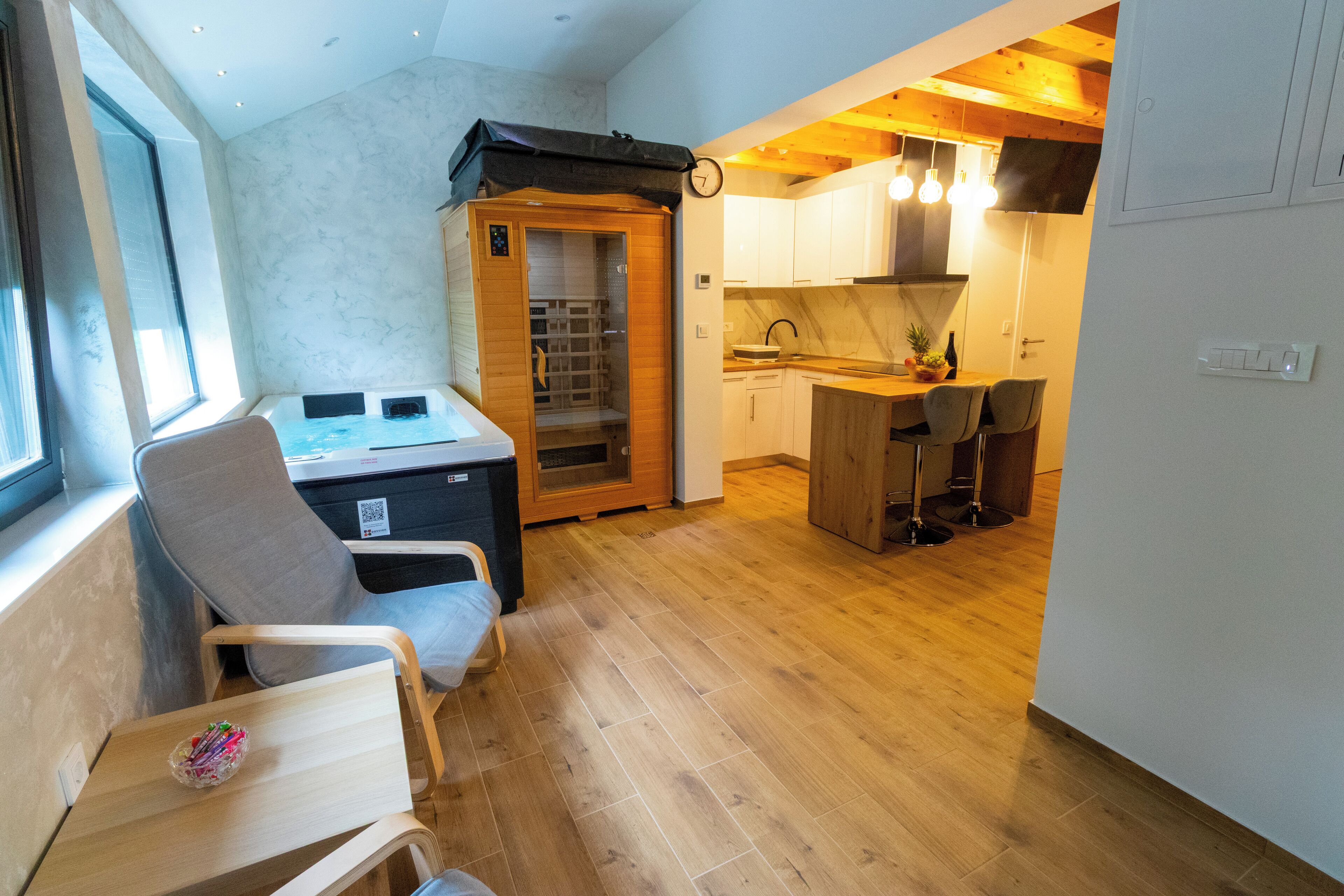 A compact kitchen with wooden cabinets, a dining area with chairs, and a sauna.