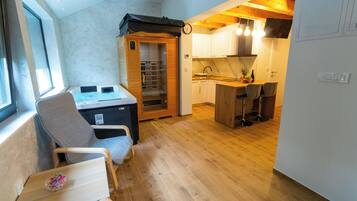 A compact kitchen with wooden cabinets, a dining area with chairs, and a sauna.