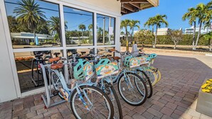 Una hilera de bicicletas con letreros que dicen 'Book & Save' estacionadas frente a un edificio de grandes ventanales.
