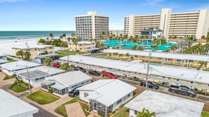 Un hotel con edificios de varios pisos, un estacionamiento y vista a la playa.