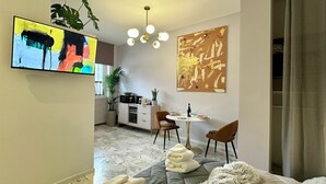 A modern living room with a sofa, a dining table with chairs, a TV, and artwork on the walls. - Elegant and Private, close to the city center. Gran Dimora dei Sensi e Charme. (Bergamo)