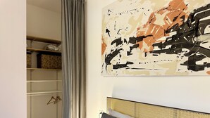 A bedroom with a bed, a headboard, a wall-mounted abstract painting, and a wardrobe with a mirror. - Elegant and Private, close to the city center. Gran Dimora dei Sensi e Charme. (Bergamo)