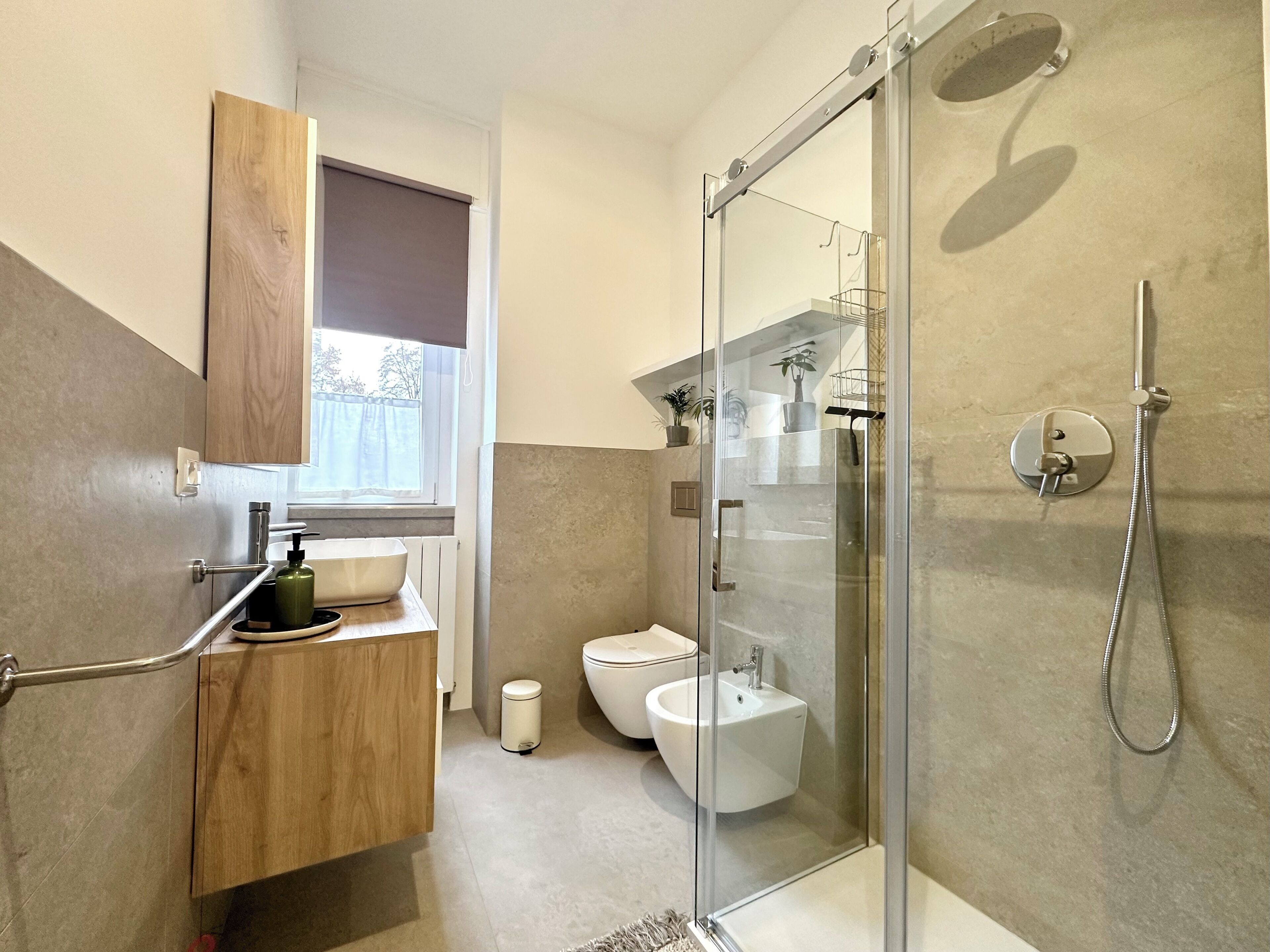 A modern bathroom with a glass shower enclosure, a toilet, a sink, and a wooden vanity.