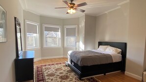 A bedroom with a bed, a ceiling fan, a window, and a radiator. - Family friendly neighborhood spacious 3-bedrooms, 2 baths,  parking, near train. (Brookline)