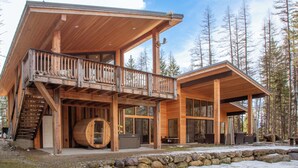 Una cabaña de madera con balcón, jacuzzi y pared de piedra.