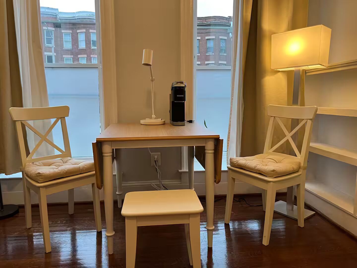 Ett hörnskrivbord med två stolar, en lampa och en kaffebryggare.