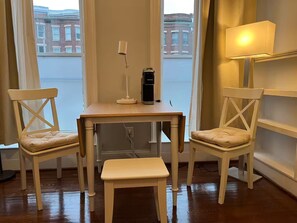 Ein Schreibtisch in der Ecke mit zwei Stühlen, einer Lampe und einer Kaffeemaschine.