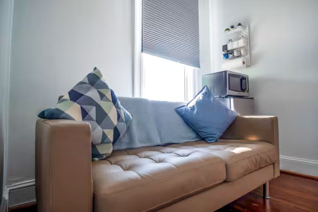 A beige sofa with a patterned pillow, a blue pillow, and a small table with a television.