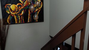 Una escalera con barandillas de madera y un cuadro con elefantes coloridos en la pared.