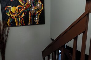 Eine Treppe mit hölzernen Geländern und einem Wandbild bunter Elefanten.