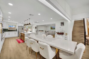 Une cuisine moderne avec des meubles blancs, un îlot central et des luminaires suspendus.