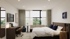 Ein Hotelzimmer mit Bett, Schreibtisch, Stuhl, Fernseher und großen Fenstern.