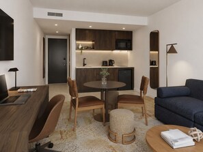Una sala de estar moderna con una mesa de comedor, sillas, un sofá y una zona de cocina con microondas.