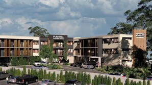 Ein modernes Gebäude mit der Beschilderung 'PUNTHILL APARTMENT HOTELS', das einen Parkplatz mit mehreren Autos und eine bepflanzte Grünfläche mit Bäumen zeigt.