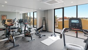 Ein modernes Fitnessstudio mit unterschiedlichen Trainingsgeräten, großen Fenstern und freiem Blick nach draußen.