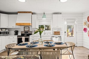 A kitchen with white cabinets, a wooden ceiling, a dining table with chairs, and a vase with a plant. - New Listing! Short walk to Perfect Laguna Beach!  Covered Patio~ Quiet Community (Panama City Beach)