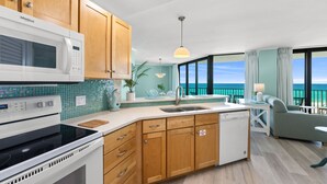 A kitchen with a microwave, stove, and dishwasher, wooden cabinets, a sink, and a view of the ocean. - New Listing!   Fall Specials & Free Beach Chair Service ~ 3rd Floor (Panama City Beach)
