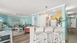 A modern kitchen with a central island, bar stools, and a dining area with a table and chairs. - New Listing!   Fall Specials & Free Beach Chair Service ~ 3rd Floor (Panama City Beach)