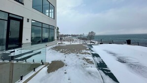 Un bâtiment moderne doté de grandes fenêtres, dont le sol est recouvert de neige, et qui offre une vue sur la mer.