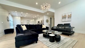 Un salon moderne avec un canapé d’angle, une table basse et un lustre.