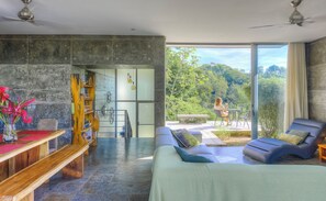Un interior moderno con cama, zona de estar y vistas a un jardín.
