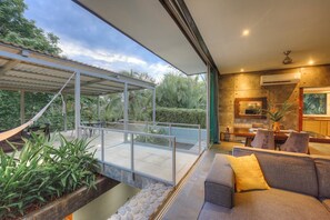 A modern interior with a dining area, a sofa, and a view of the outdoors. - Villa Los Laureles I, Private Pool • Trails • Beaches (Bejuco)