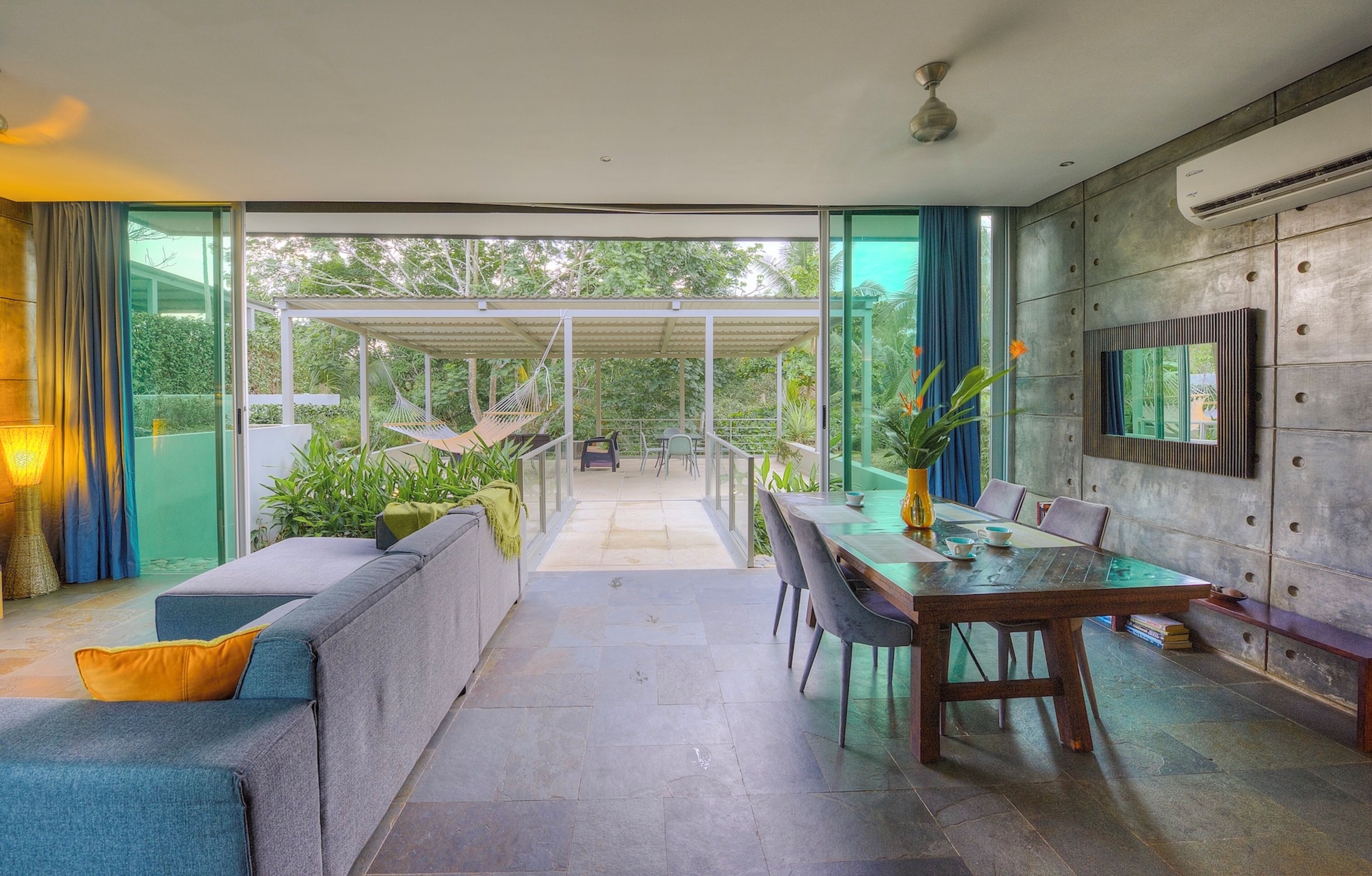Ein modernes Interieur mit Essbereich, Sofa und Blick durch eine Glastür in einen Außenbereich.
