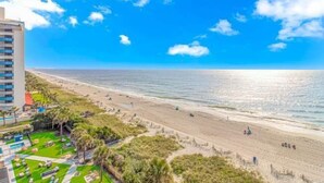 Vista de una playa con un hotel, cielo despejado y océano.