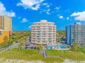 A hotel with a circular building, a swimming pool, and a parking area. - St. Clements 602 (Myrtle Beach)