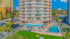 Un hotel de varios pisos con zona de piscina, mobiliario exterior y vistas despejadas del entorno.