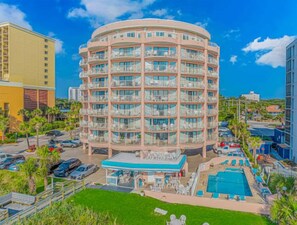 A multi-story hotel with a pool area, outdoor seating, and a clear view of the surrounding area. - St. Clements 602 (Myrtle Beach)