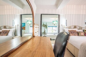 A hotel room with a wooden table, two beds, a large mirror, and a view of the bathroom. - The Old Bakery, Wrentham (Wrentham)