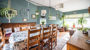 Una stanza accogliente con un letto, sedie di legno, un tavolo da pranzo e piante sospese.