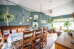 A cozy room with a bed, wooden chairs, a dining table, and hanging plants. - The Old Bakery, Wrentham (Wrentham)