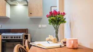 Et køkken med komfur, en vase med blomster, en kage og en notesbog på bordet.