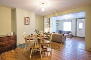 A dining area with a wooden table and chairs, a sofa, and a door leading to another room. - 40 Grimsey Road, Leiston (Suffolk)