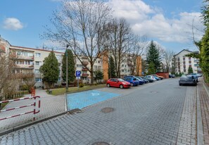 A residential street with parked cars, a blue disabled parking sign, and apartment buildings.