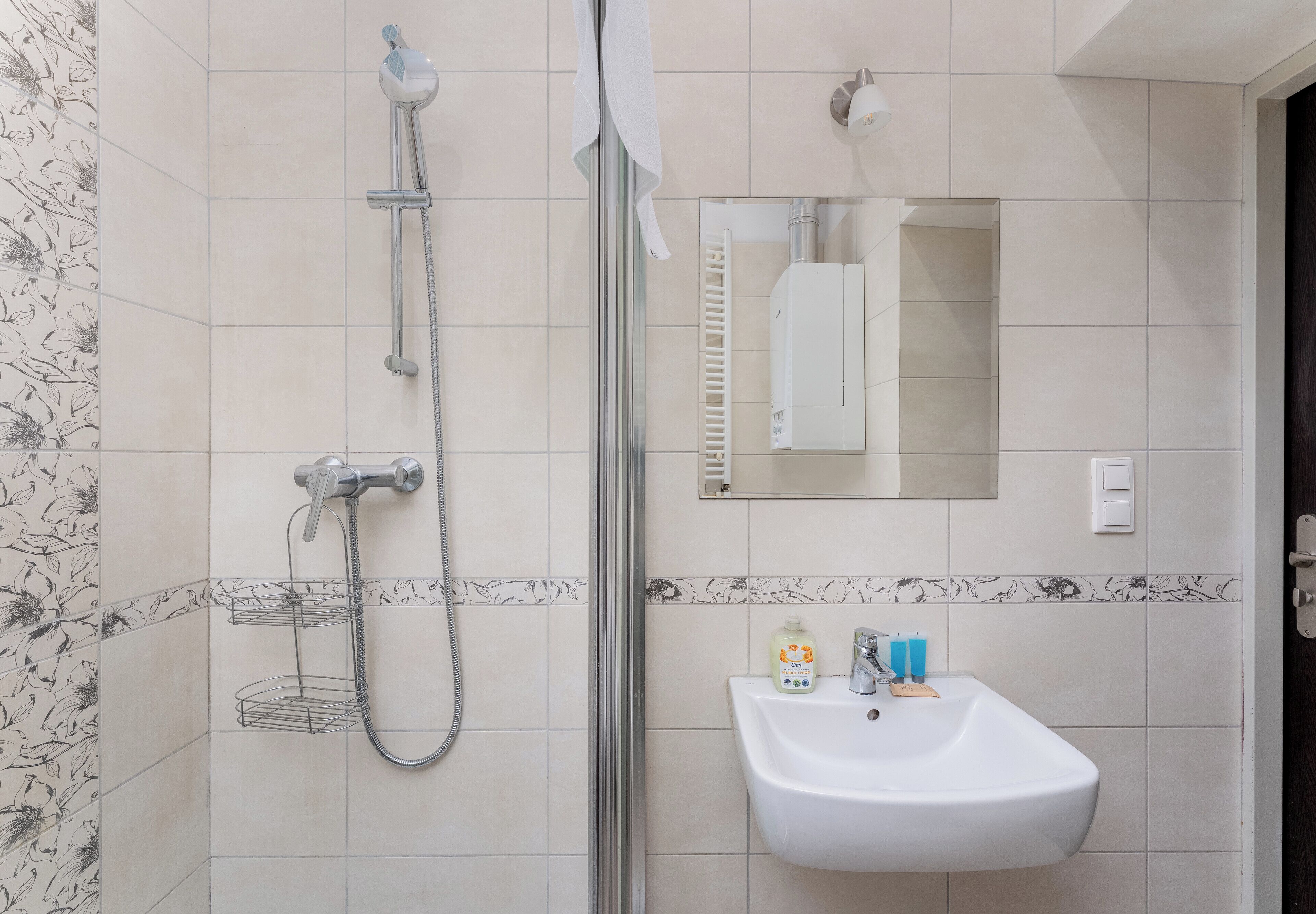 Une salle de bain équipée d’une douche, d’un lavabo, d’un miroir et d’un porte-serviettes.