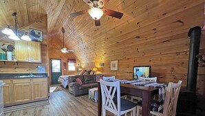 Een houten chalet van binnen, met een keuken, eethoek en woonkamer.