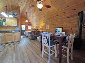 A wooden cabin interior with a kitchen, dining area, and living room. - Hideaway Cabin Bryson City, NC - 5 Minutes from Downtown (Bryson City)