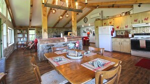 A rustic farmhouse interior with a wooden dining table, a kitchen with wooden cabinets, and a stone fireplace. - View 280- Amazing views of the Smoky Mountains (Bryson City)