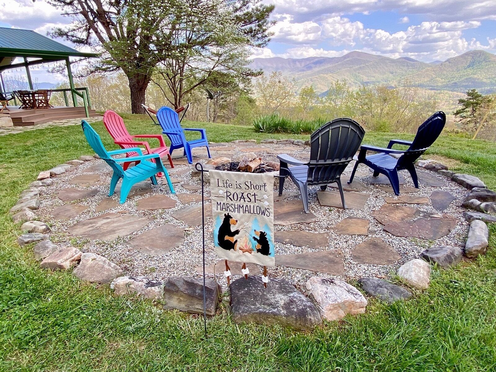 Een vuurplaats met Adirondack stoelen en een bord met een beerillustratie.