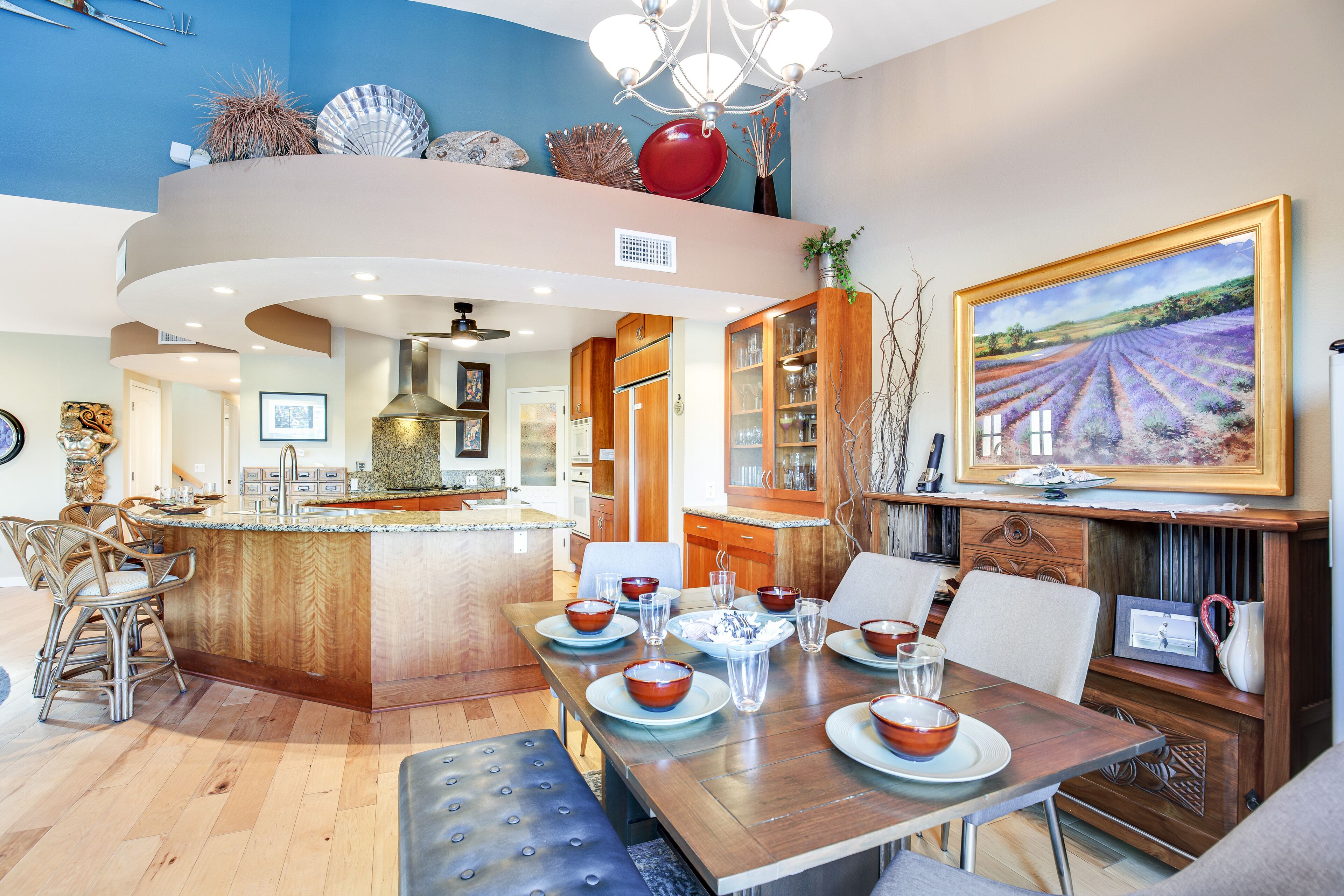 Een moderne keuken met een centraal eiland, houten kastjes en een eethoek met een tafel voor vier personen.