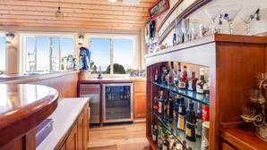A bar area with a wooden ceiling, a refrigerator, and a glass shelf with various bottles. - Long Time No Sea Walk to Beach (Encinitas)