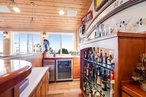 Eine Bar mit Holzbalkendecke, einem Kühlschrank und einer Glasablage mit verschiedenen Flaschen.
