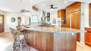 A kitchen with a large island, wooden cabinets, and a ceiling fan. - Long Time No Sea Walk to Beach (Encinitas)