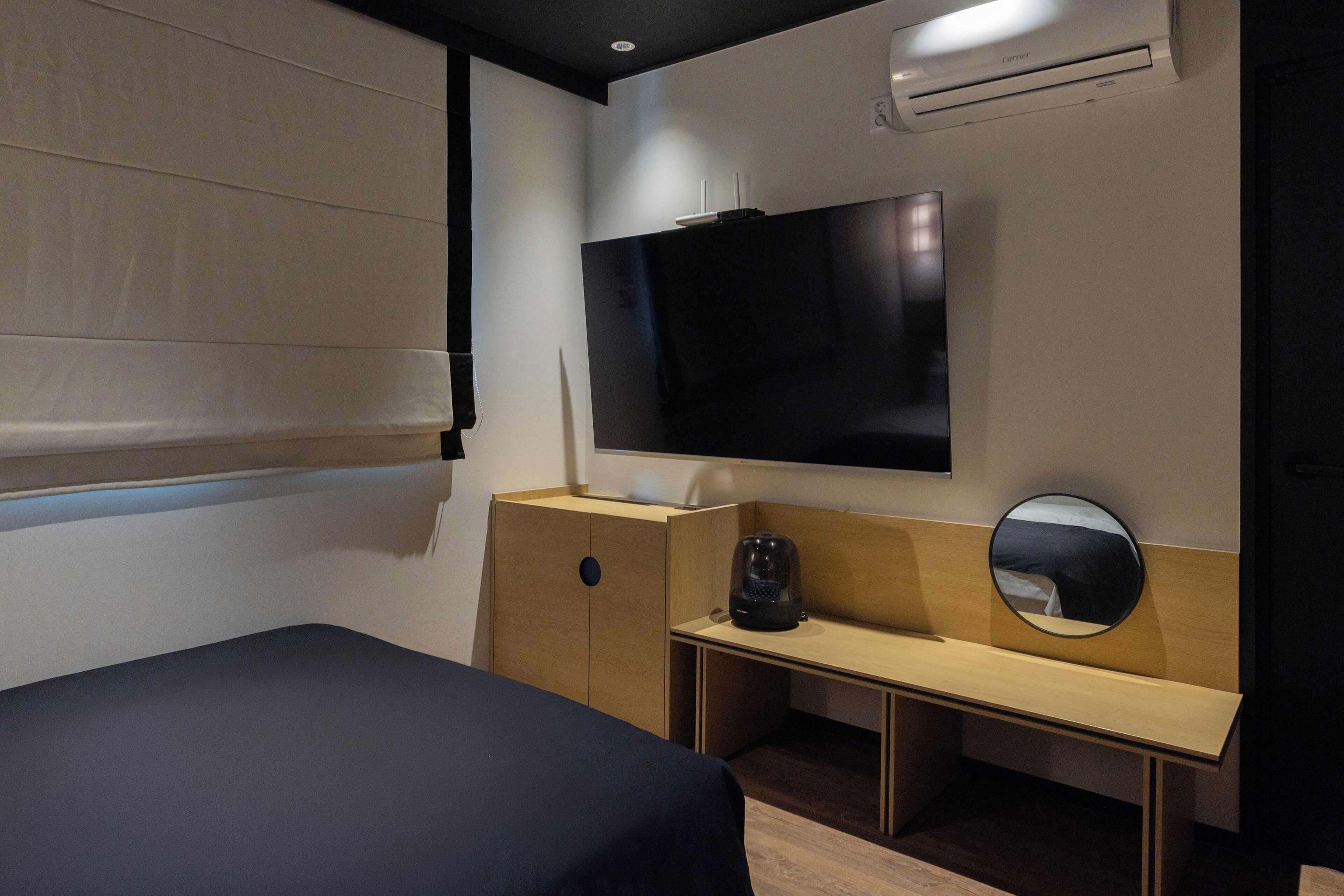 Una camera d'albergo con un letto, una scrivania, una televisione e un condizionatore.